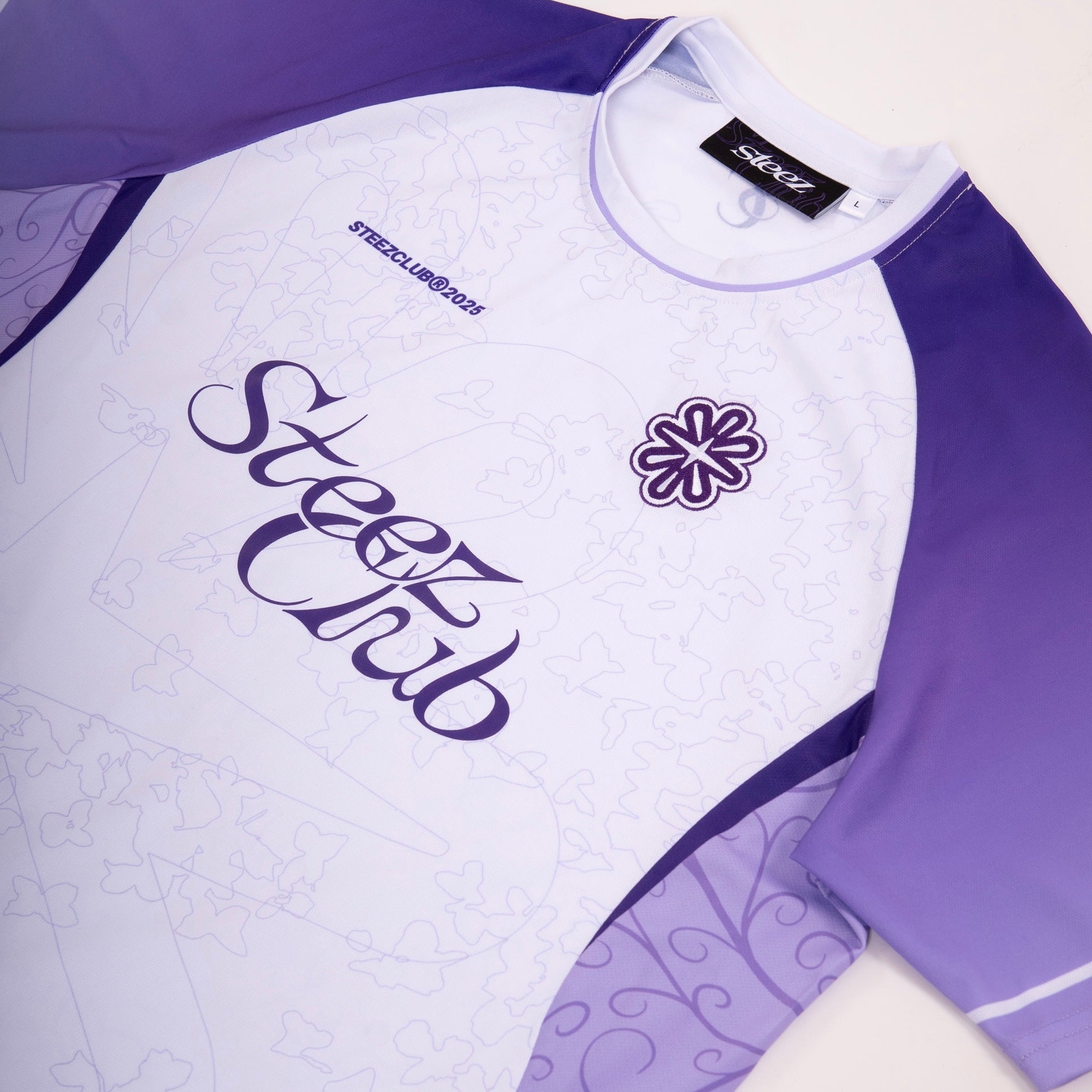Gros plan sur le maillot Steez Club blanc et violet - Détails du design avec logo brodé, imprimé subtil et manches raglan. Tissu respirant idéal pour un style streetwear, sportif et pour l'été.